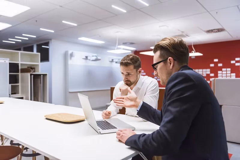 two businessmen sitting in a modern office discussing cybersecurity
