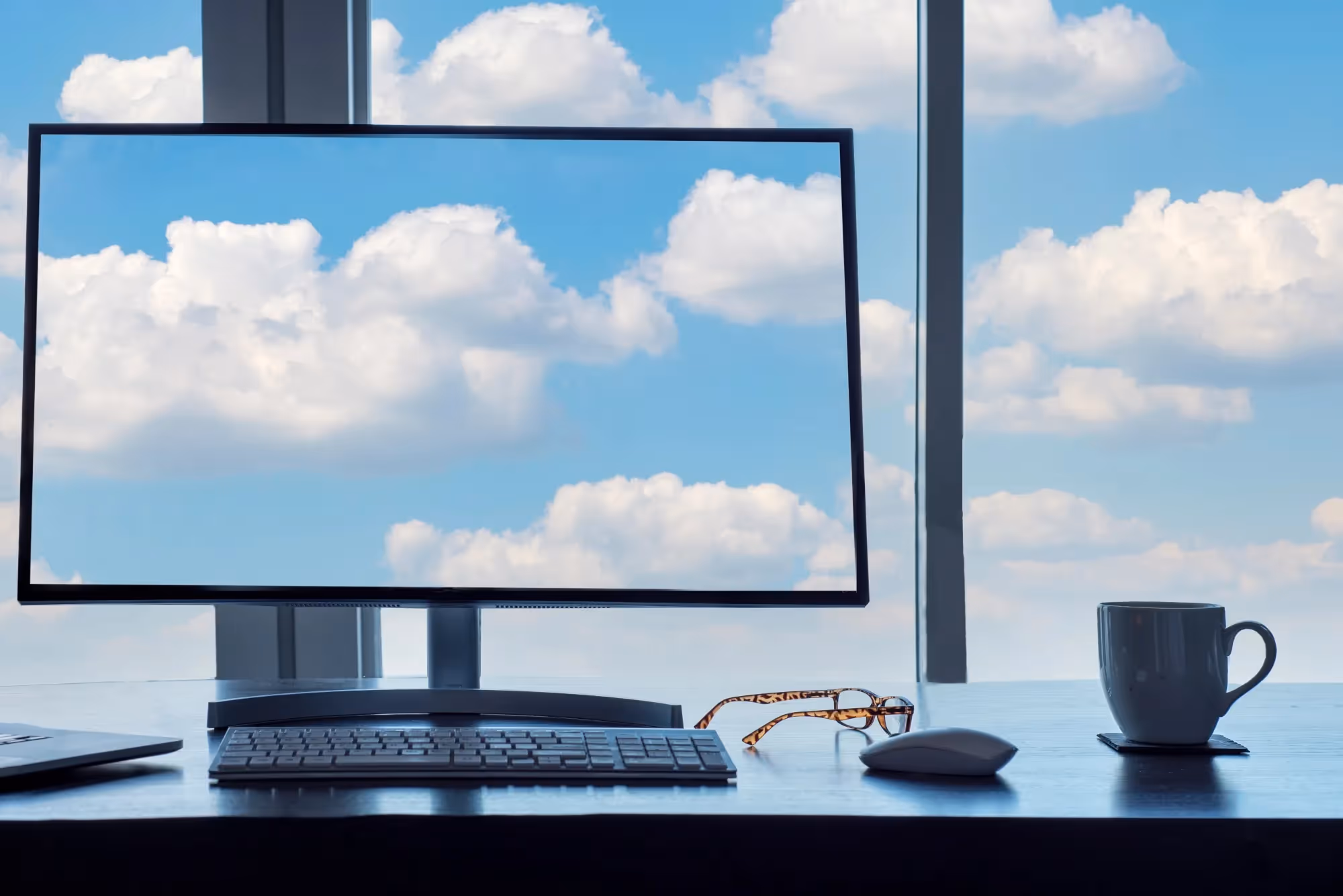 Desktop computer displaying the same cloud that is visible outside the window