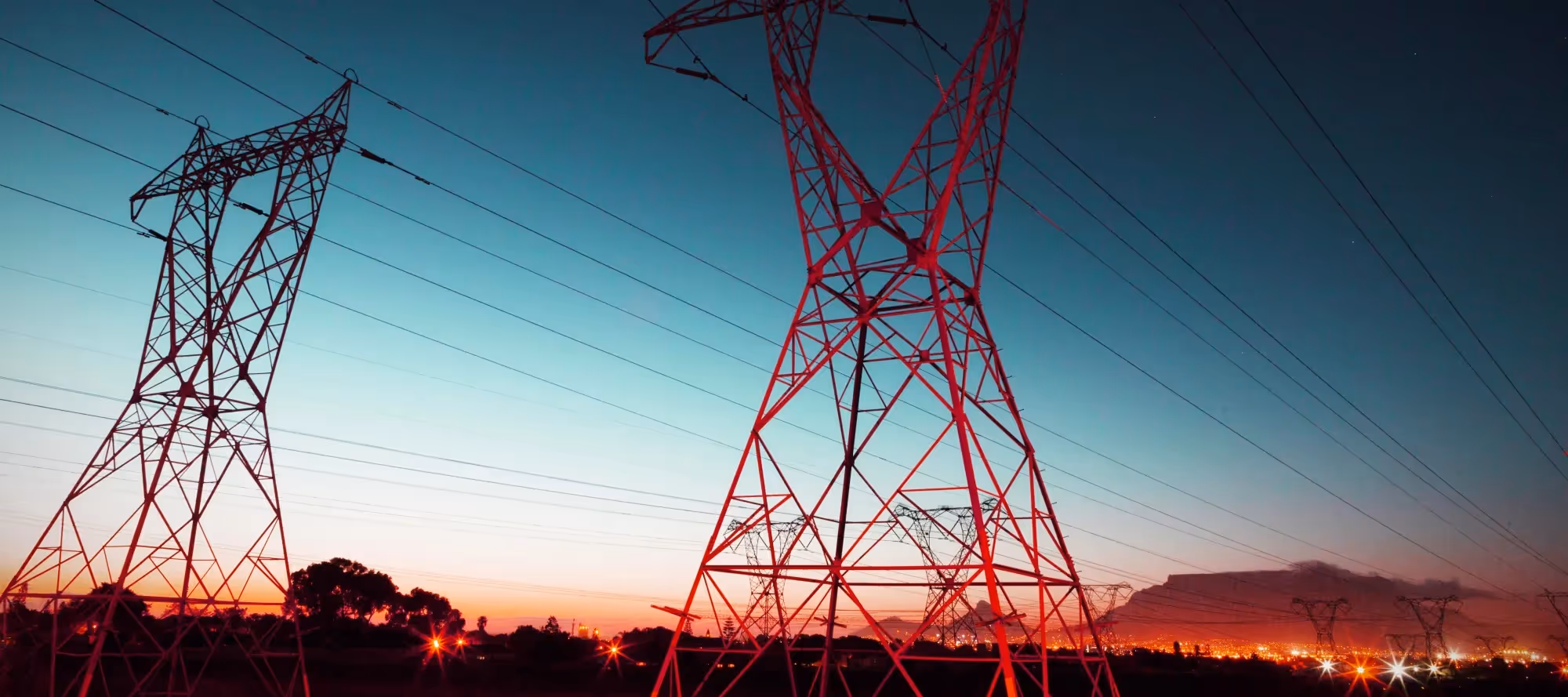 An evening photo of large pylons used to support electrical cables
