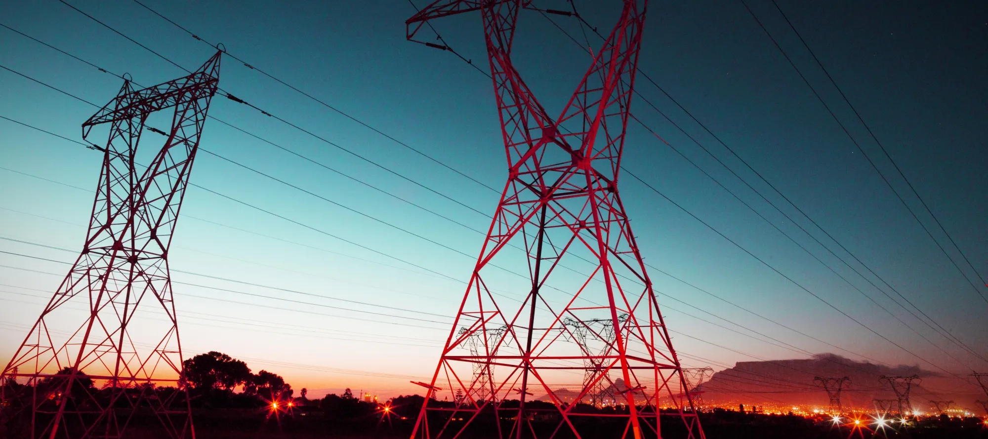 An evening photo of large pylons used to support electrical cables