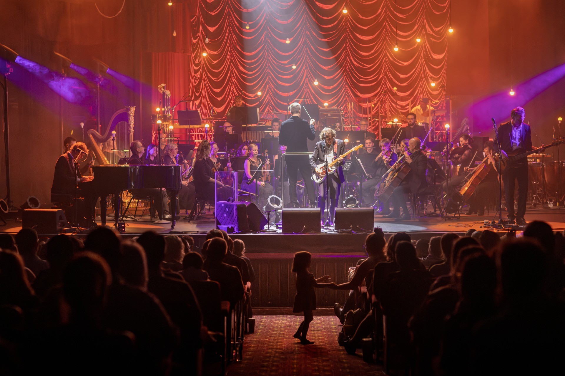 The Whitlams performing with the Sydney Symphony Orchestra to a full house under red and gold light