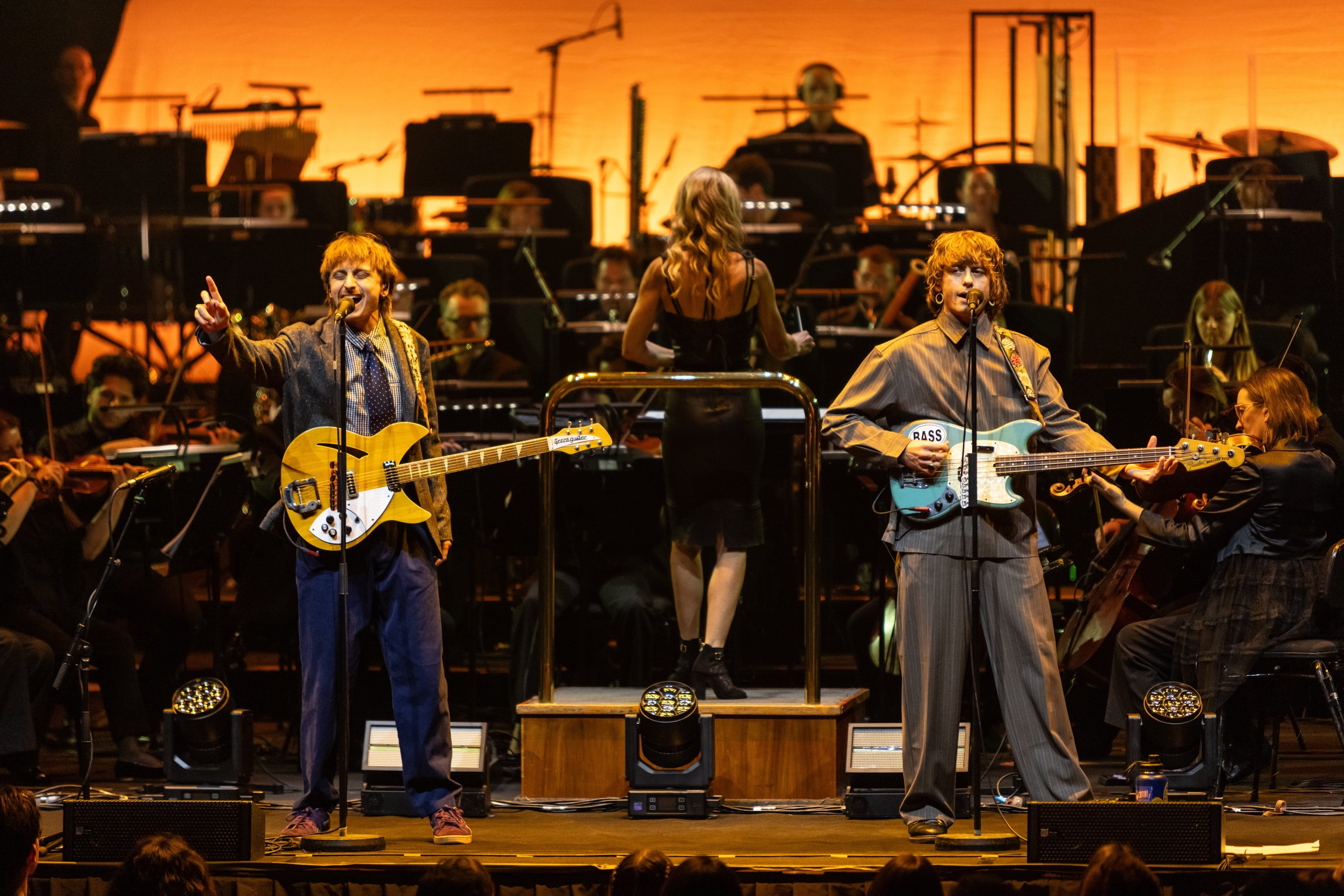Lime Cordiale on guitars in front of the Melbourne Symphony Orchestra, lit in warm orange