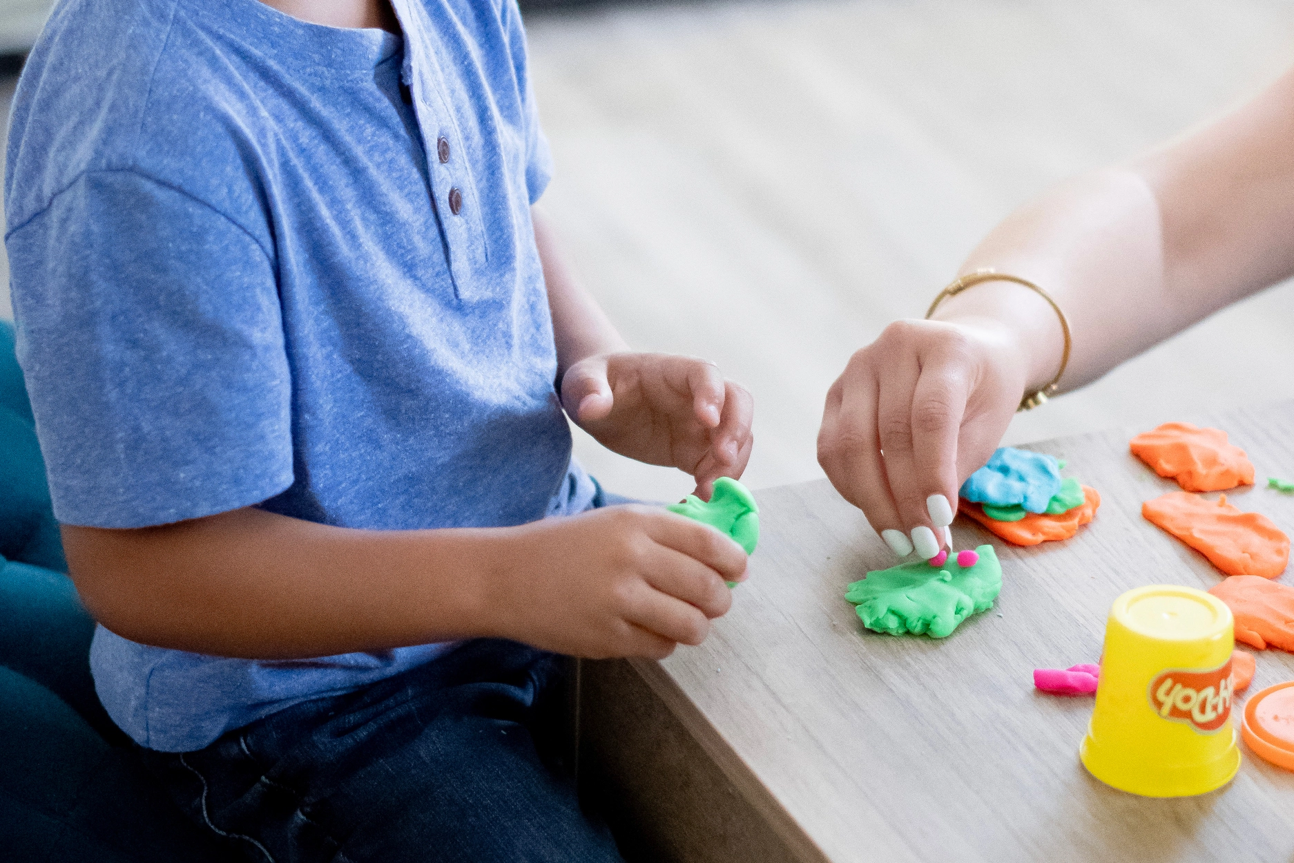 A young boy playing with playdoh during a therapy session.
