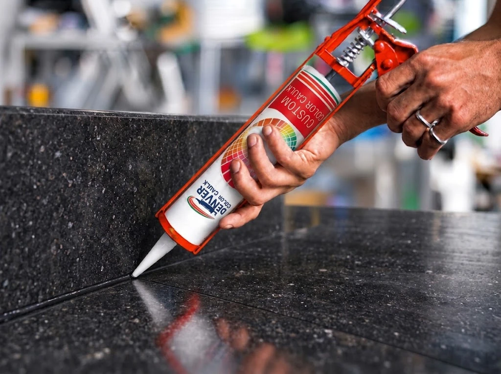 Caulking the seam of a dark granite countertop with Denver Color Caulk