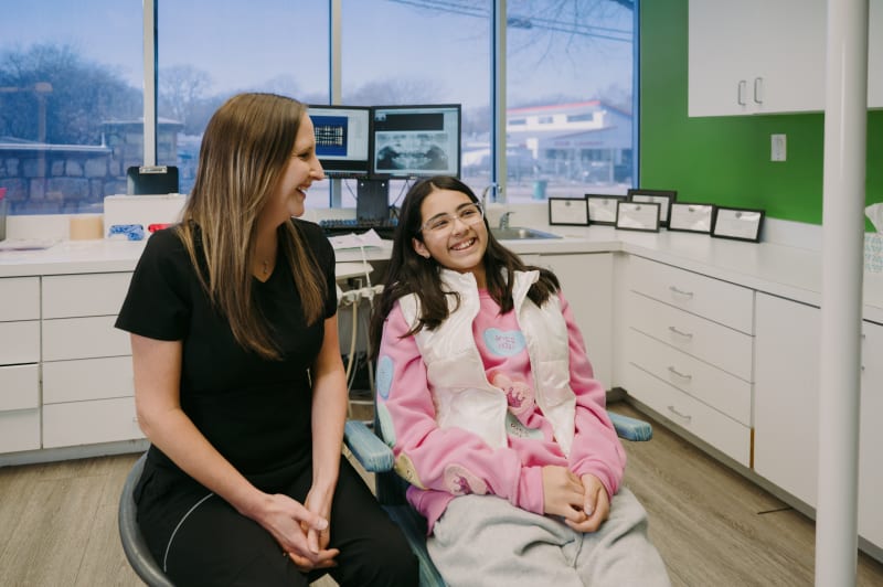 Dentist consulting with young patient and parent in treatment room during appointment discussion