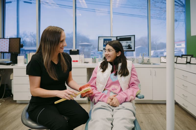Female dentist consulting with young patient in dental treatment room