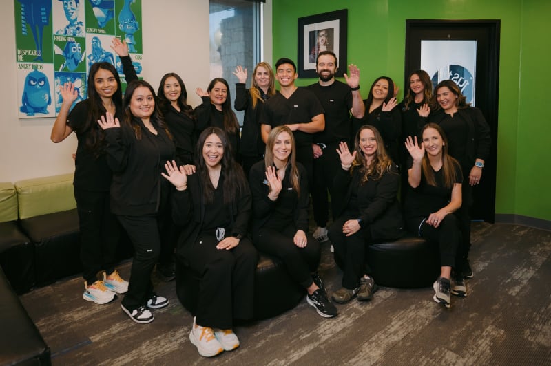 Large dental practice team in black uniforms standing together in office