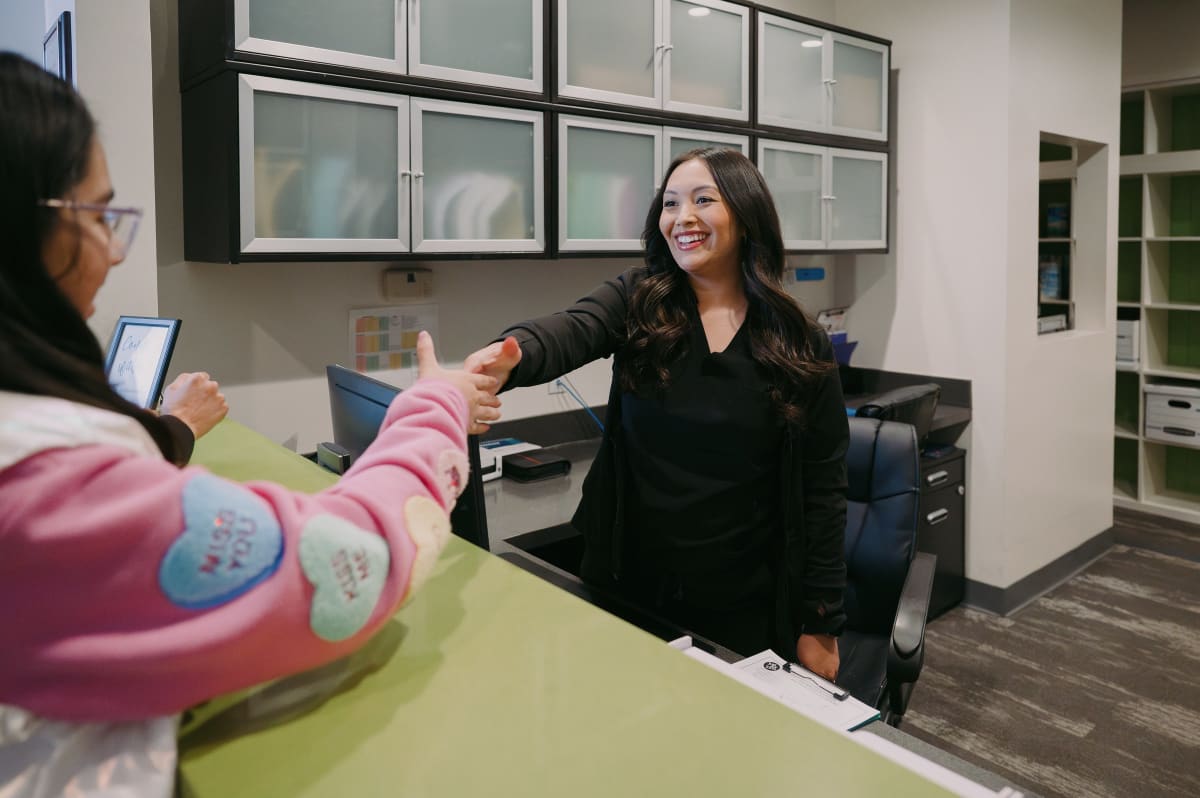 Pediatric dentist greeting a young patient in the dental office treatment room.