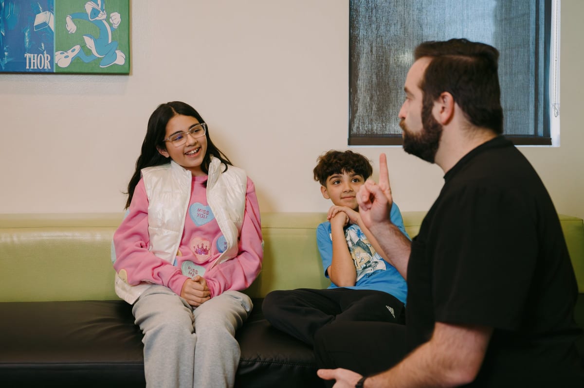 Mother and young child in dental office waiting area with dentist, preparing for appointment