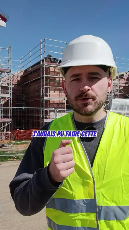 Man in a white hard hat and yellow safety vest at a construction site under clear blue sky.