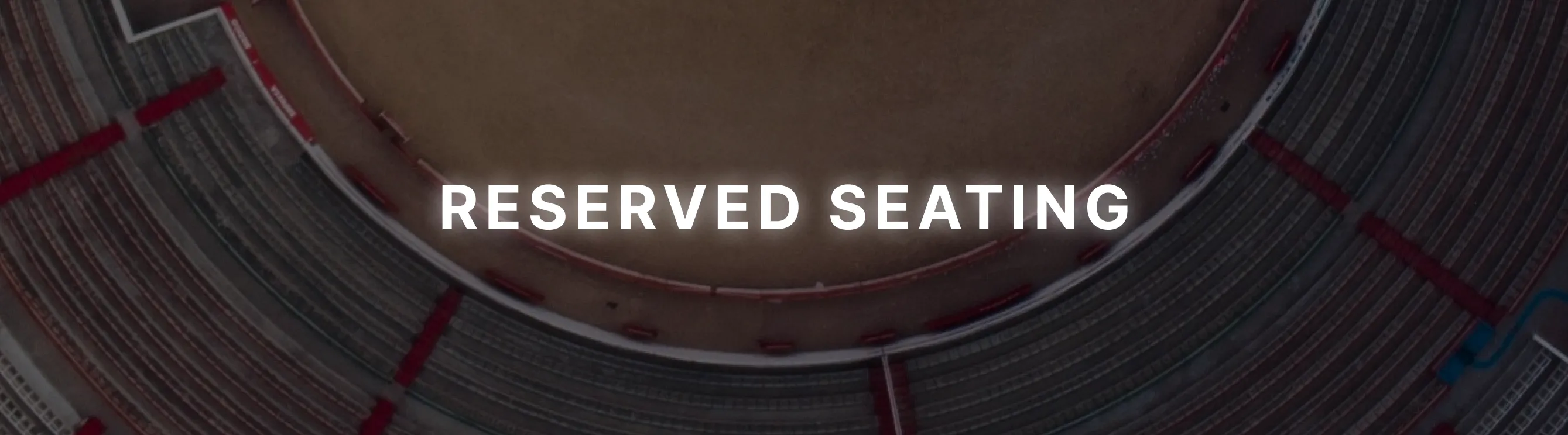 Aerial view of an empty stadium with curved rows of seating and the words 'RESERVED SEATING' in white text over the center.