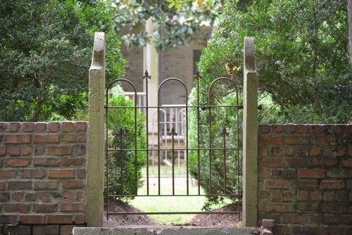 a gate with a stone wall and trees in the background