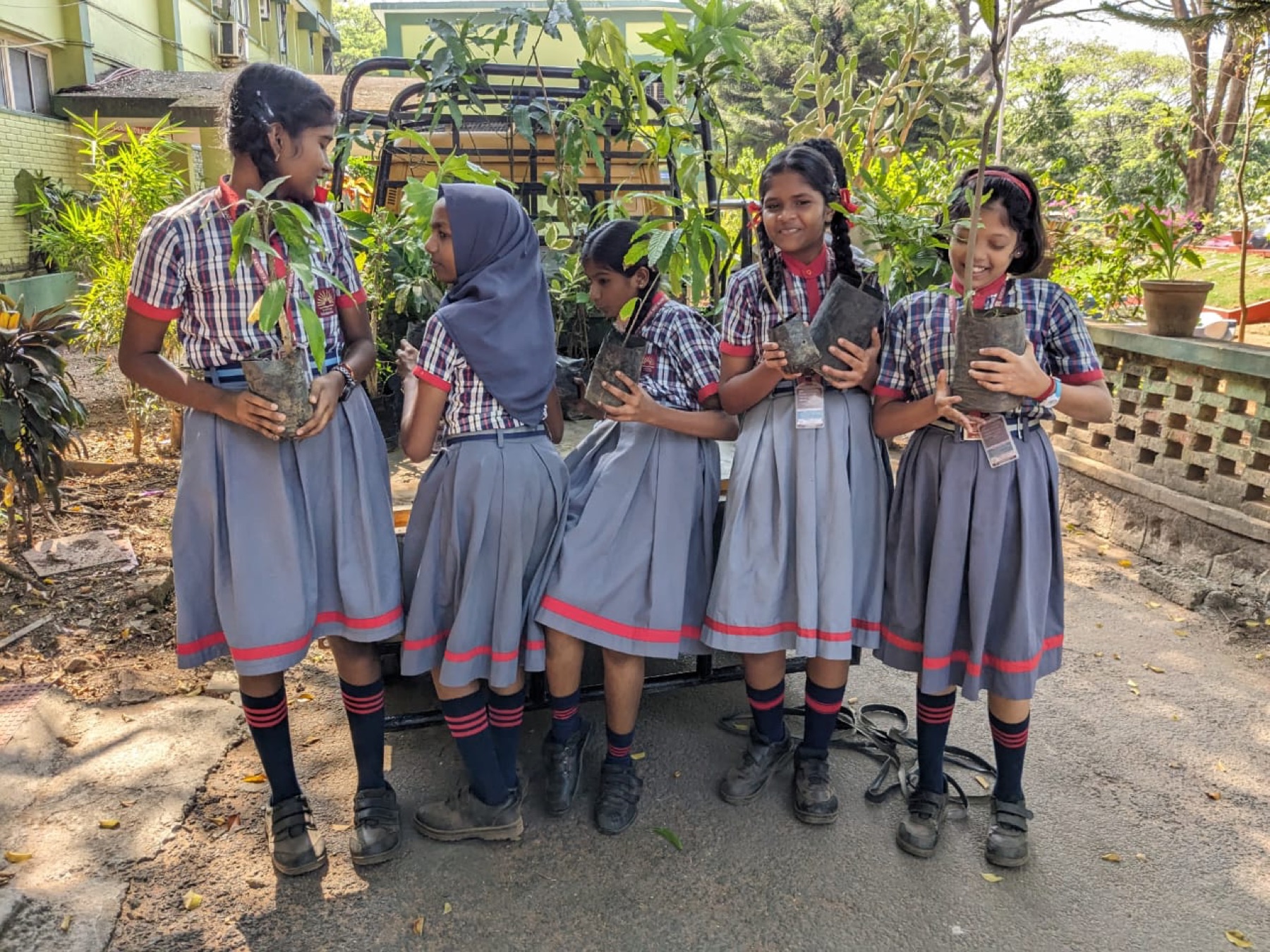 Young Green Kerala Volunteers participants stand together holding plants.