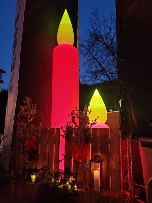 große Leuchtkerzen eingezäunt und dekoriert mit Lampen und Holzformen