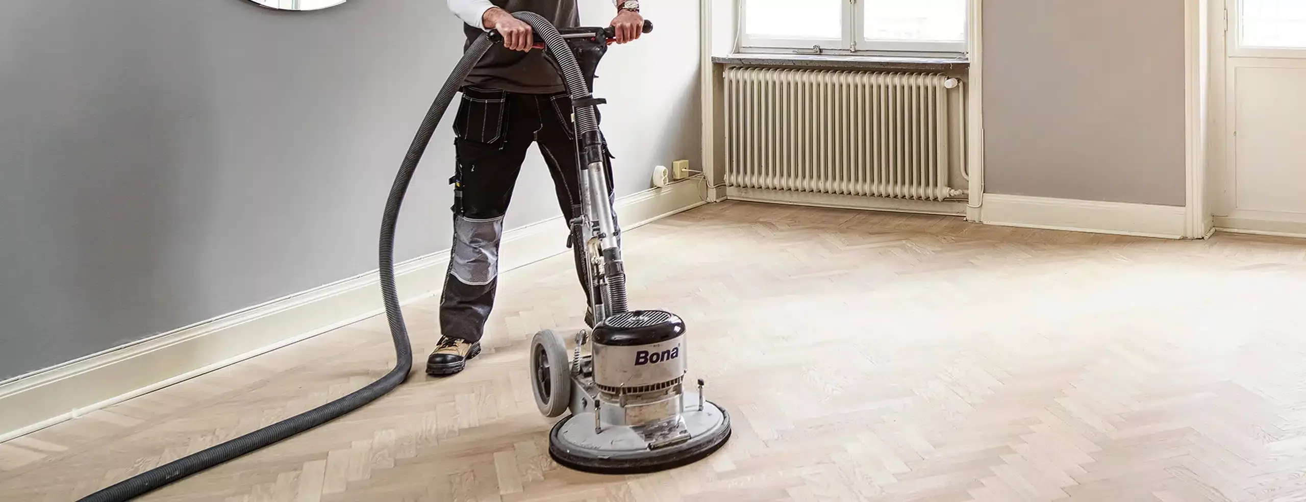 OC Flooring technician sanding out damage on a solid hardwood floor in Arlington, WA