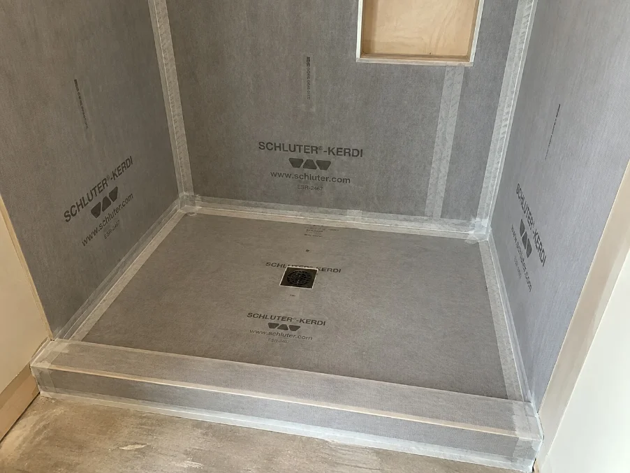 Bonded waterproofing membrane under a flood test in a Monroe shower before tile installation