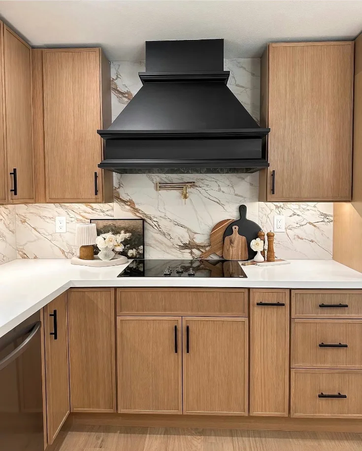 Kitchen slab backsplash in marble-look porcelain behind a black range hood