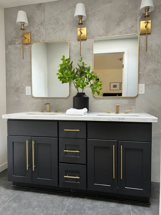 Bathroom vanity wall in grey stone-look porcelain with a black double vanity and brass sconces