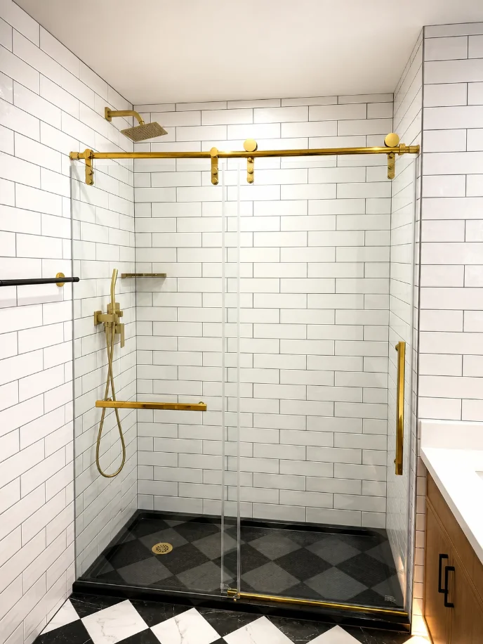 White subway tile shower with a brass sliding glass door and checkerboard pan