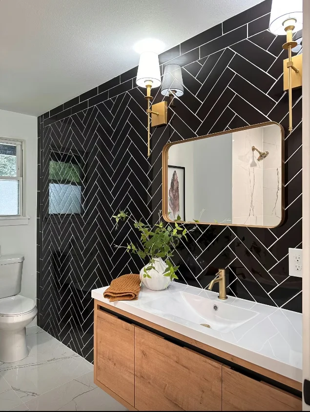 Bathroom wall in black herringbone tile with white grout, an oak vanity and marble-look floor