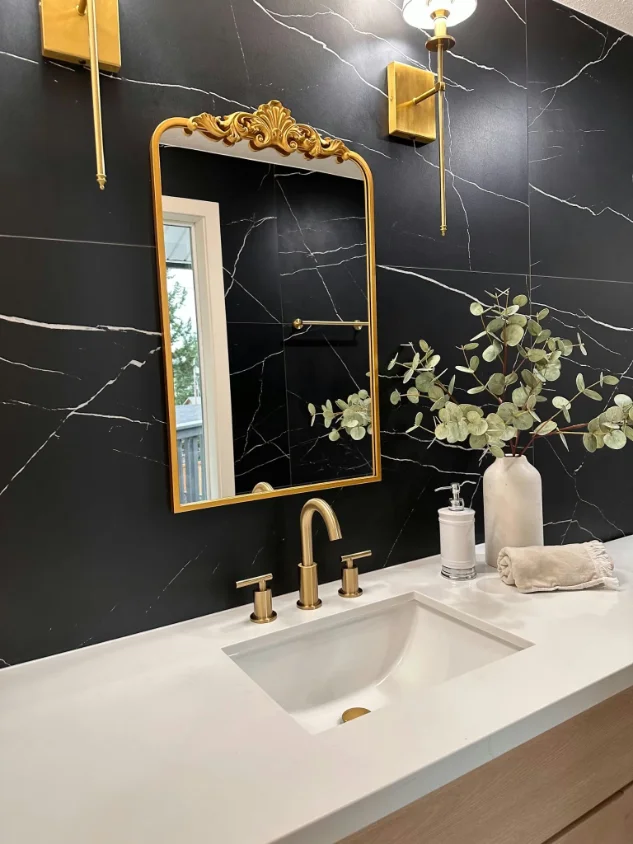 Powder room wall in black marble-look porcelain slab with an ornate gold mirror