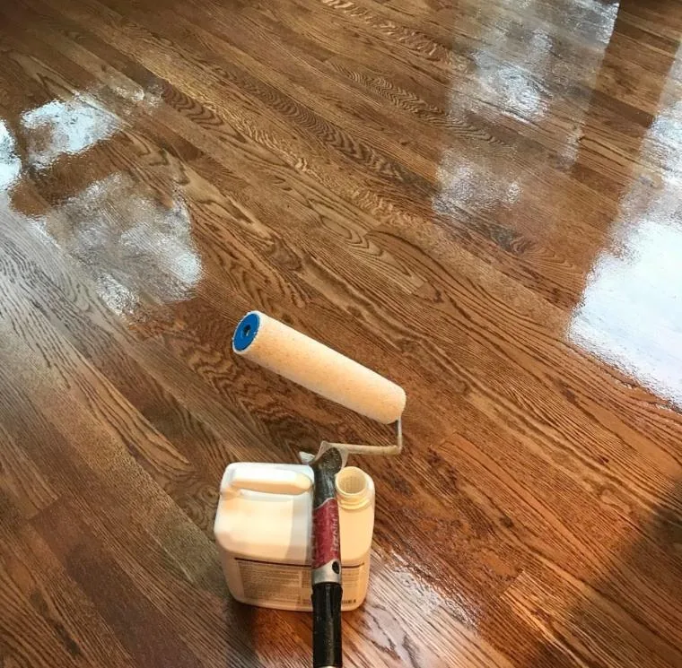 Warm mid-brown stained oak floor with finish being rolled on