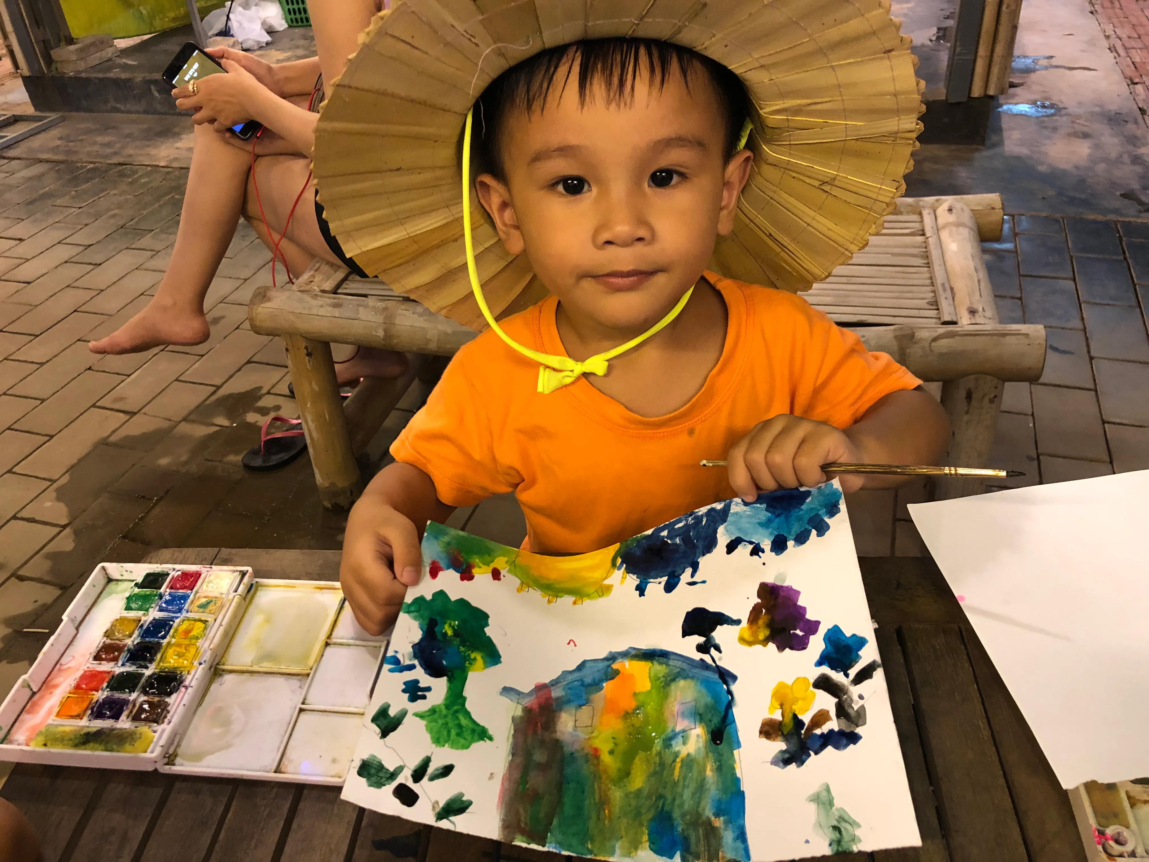 Small child holding up his painting.