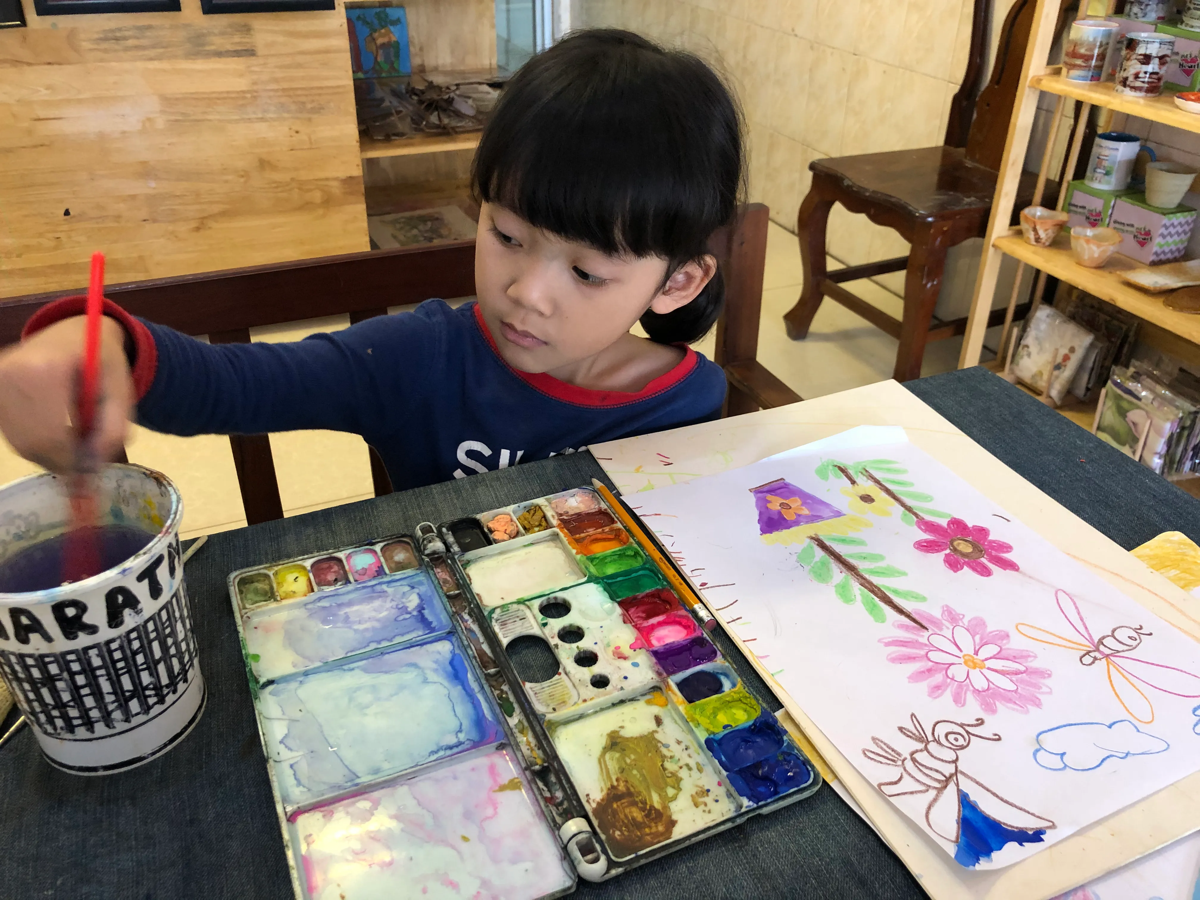 A Colors of Cambodia student painting a picture.