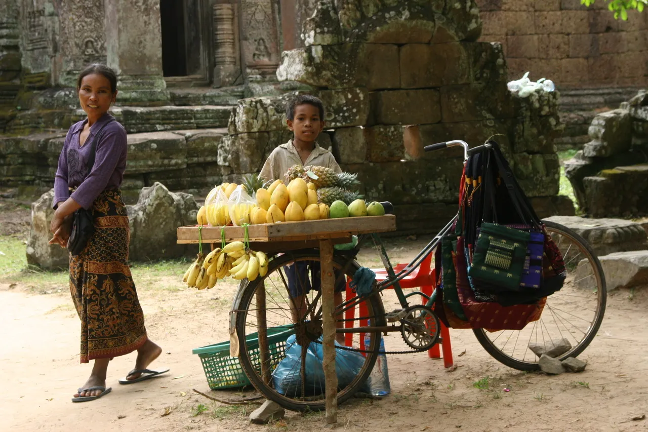 Child standing behind a fruit cart in rural Cambodia.