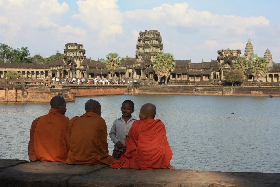 Buddhist monks at Angkor Wat overlooking a lake. 