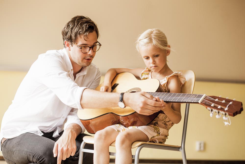 young girl learning to play the guitar, beginners guitar lesson