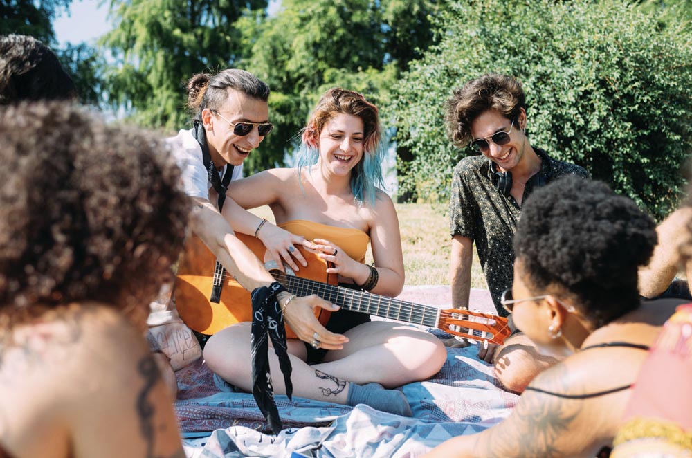 friends having a picnic, young woman playing the guitar