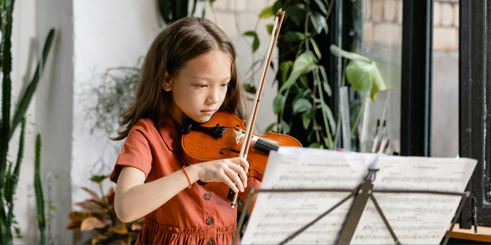 young girl playing the violin, reading music notes
