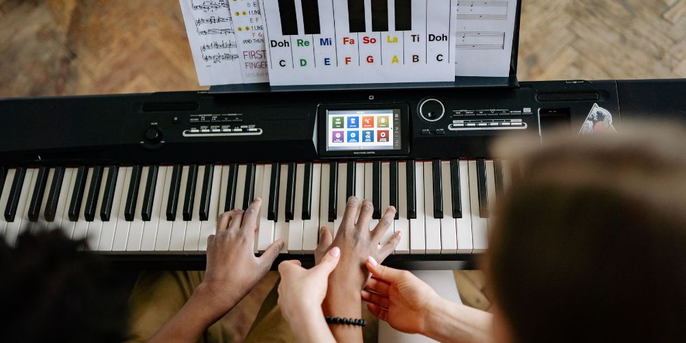 music teacher helps to place student's hand on the piano keys