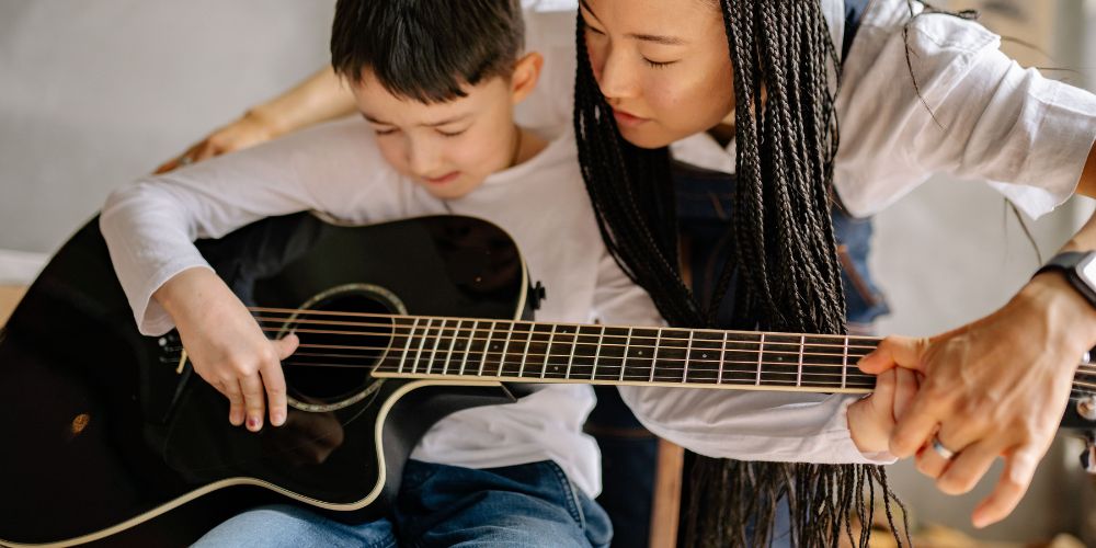 young boy playing the guitar at Ardes Music School