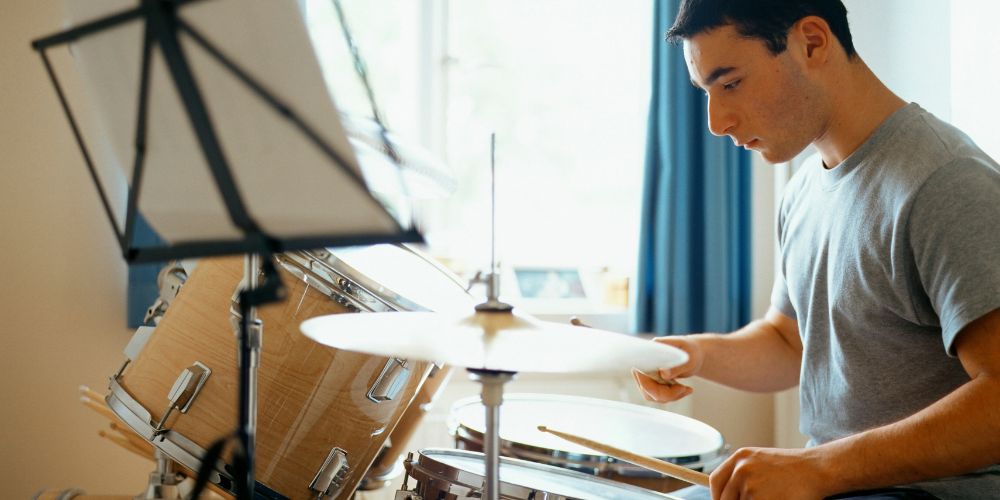 first music lessons are about getting comfortable, young guy plays drum