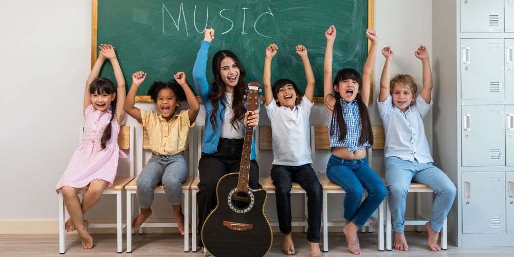 children cheer sitting with their guitar teacher