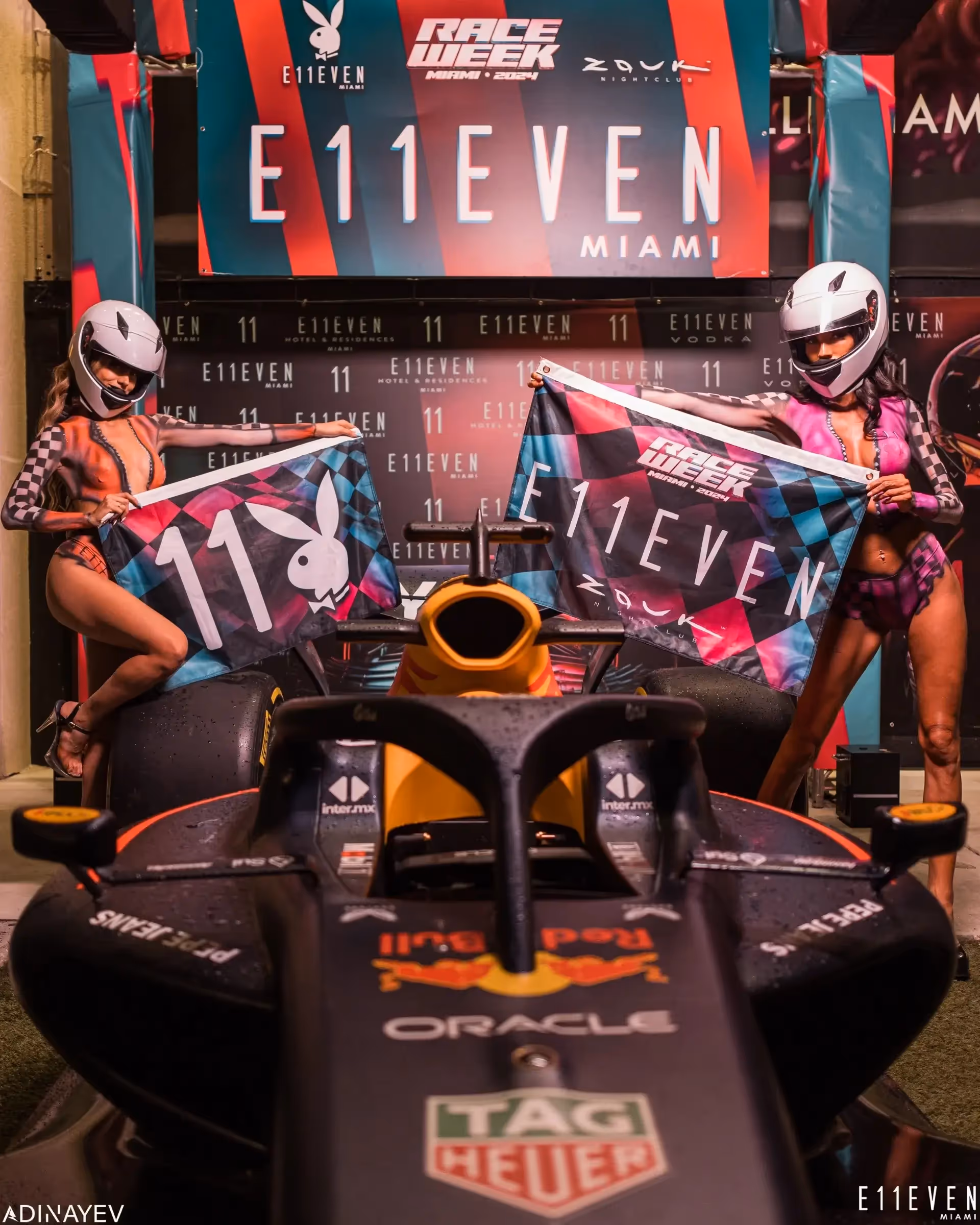 Two models holding up flags promoting Miami Race Week at E11EVEN