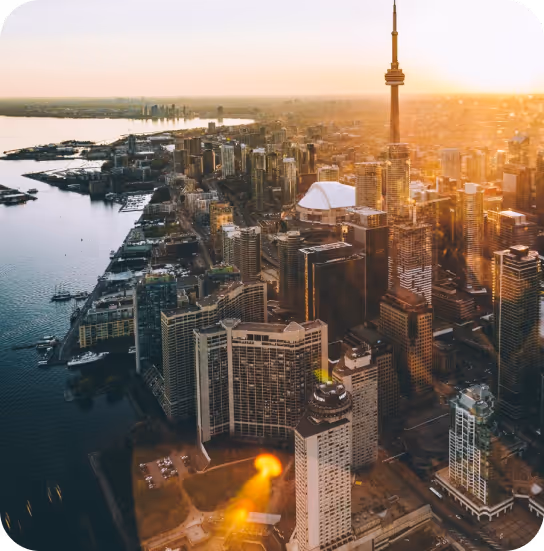 Aerial view of downtown Toronto at sunset, featuring the CN Tower and waterfront buildings.