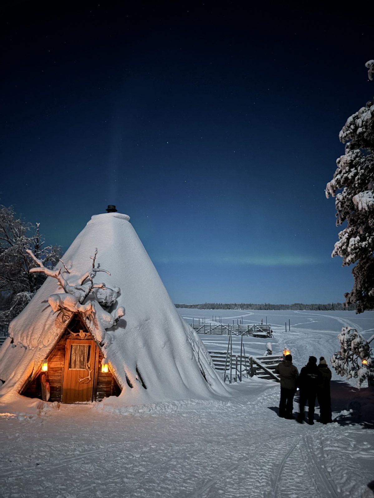 Grow Retreats Team enjoying Northern Lights and cozy evening in a traditional wooden hut by a frozen lake