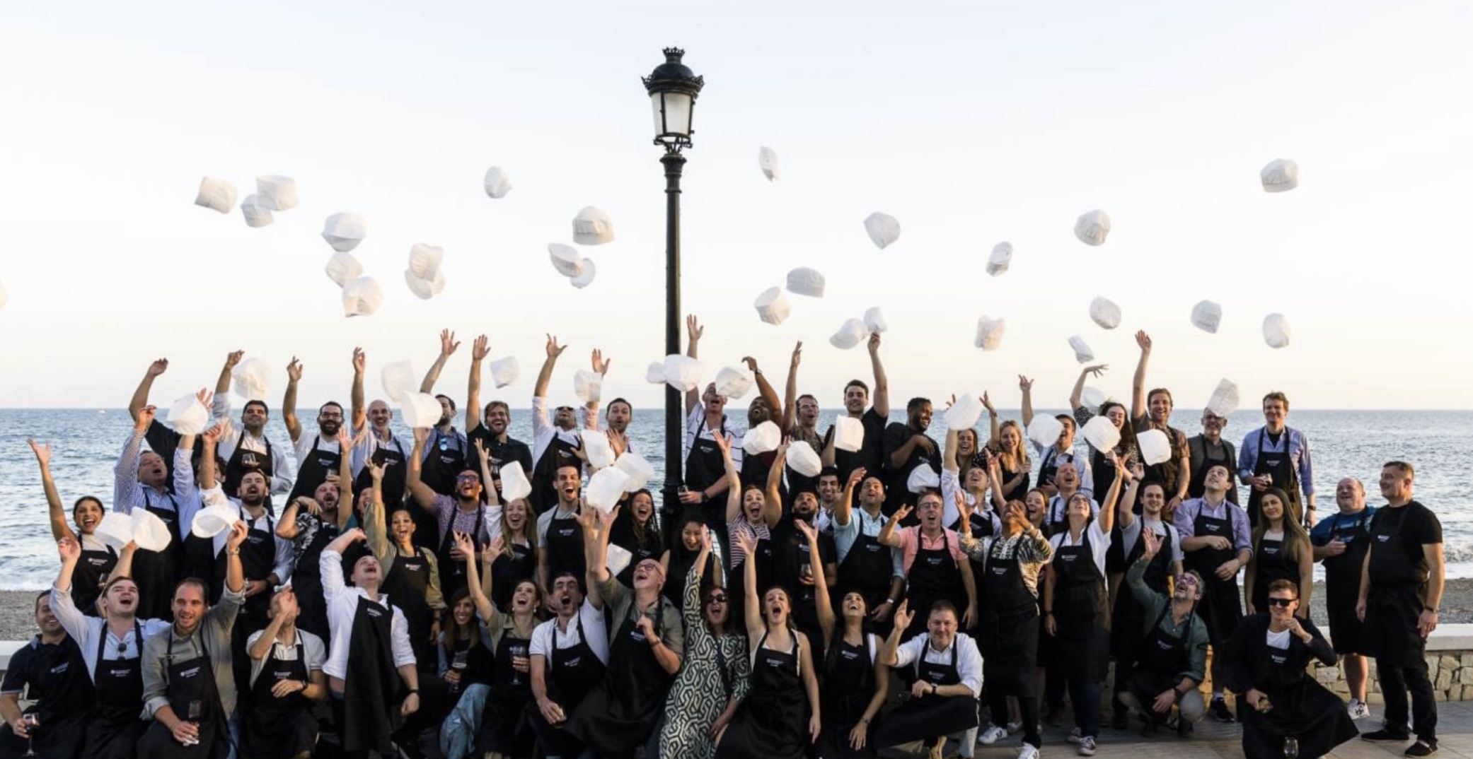 Team celebrating after the paella cooking competition during their company offsite in Marbella