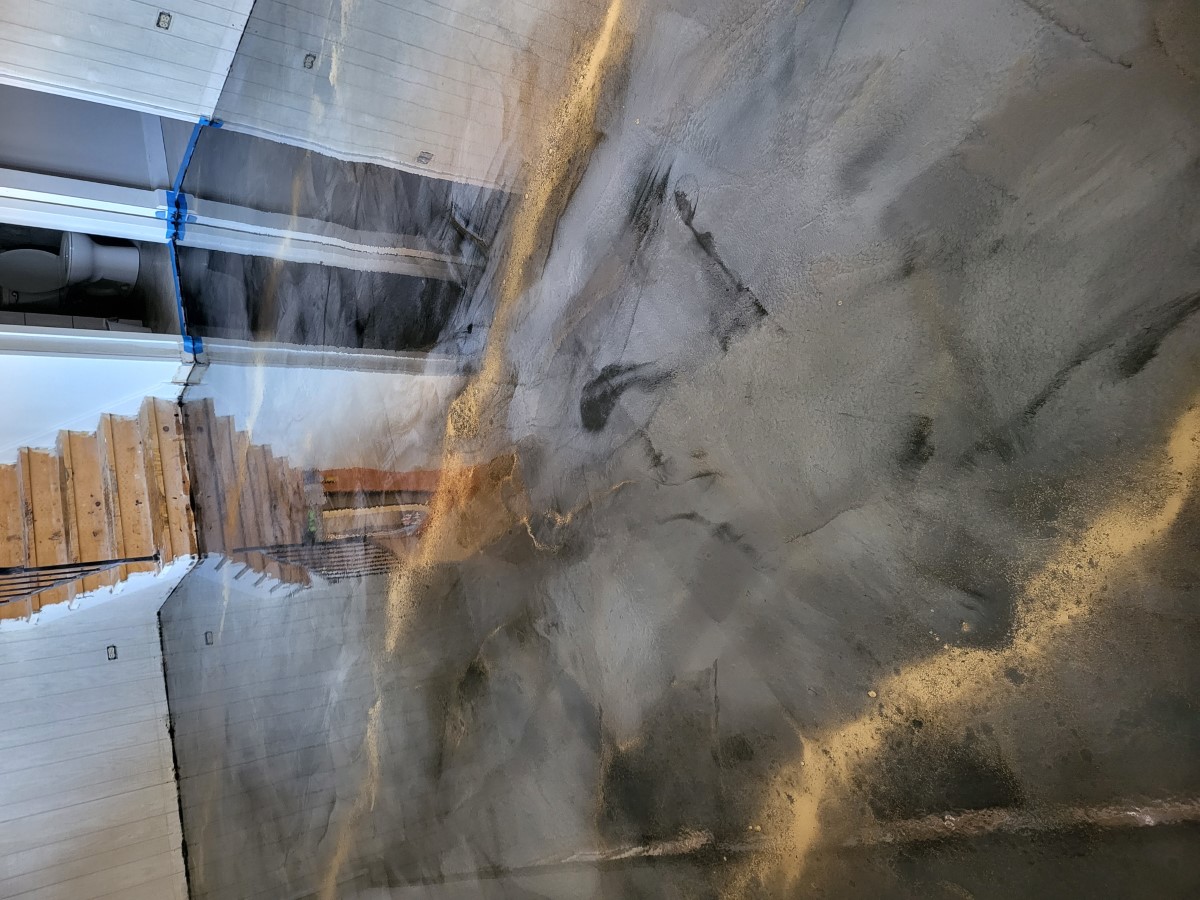 Glossy metallic epoxy floor in a small room reflecting the stairs and doorways
