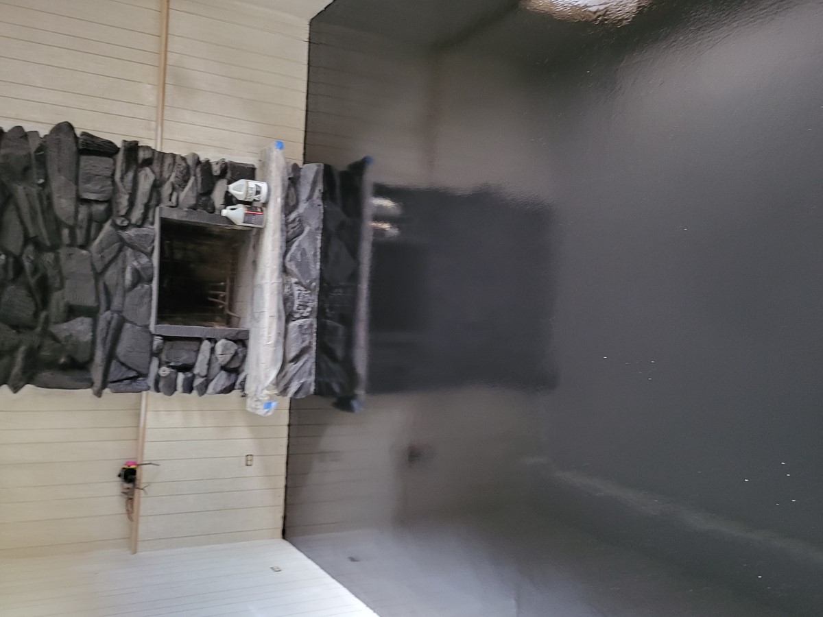 Dark metallic epoxy floor reflecting a stone fireplace and light paneled walls