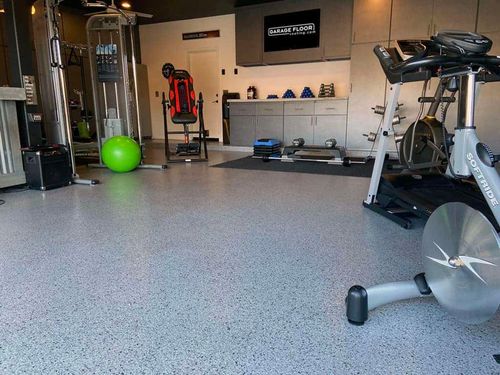Home gym with a gray epoxy flake floor and exercise equipment
