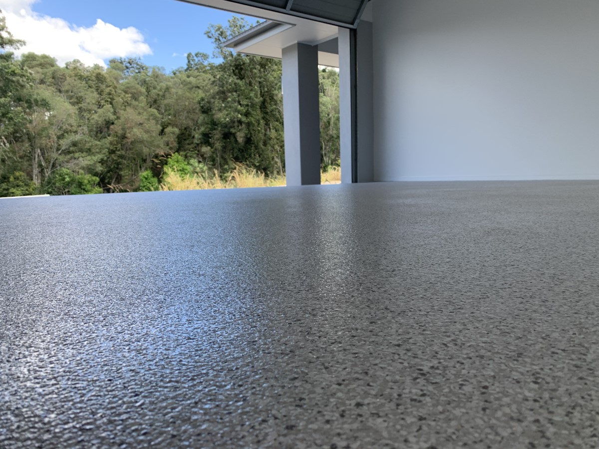 Close-up of a textured epoxy flake garage floor with the door open