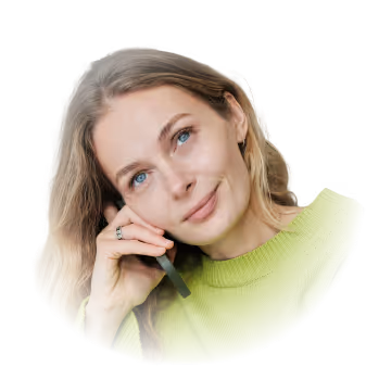 A person in a green sweater is talking on a smartphone, looking upwards slightly.