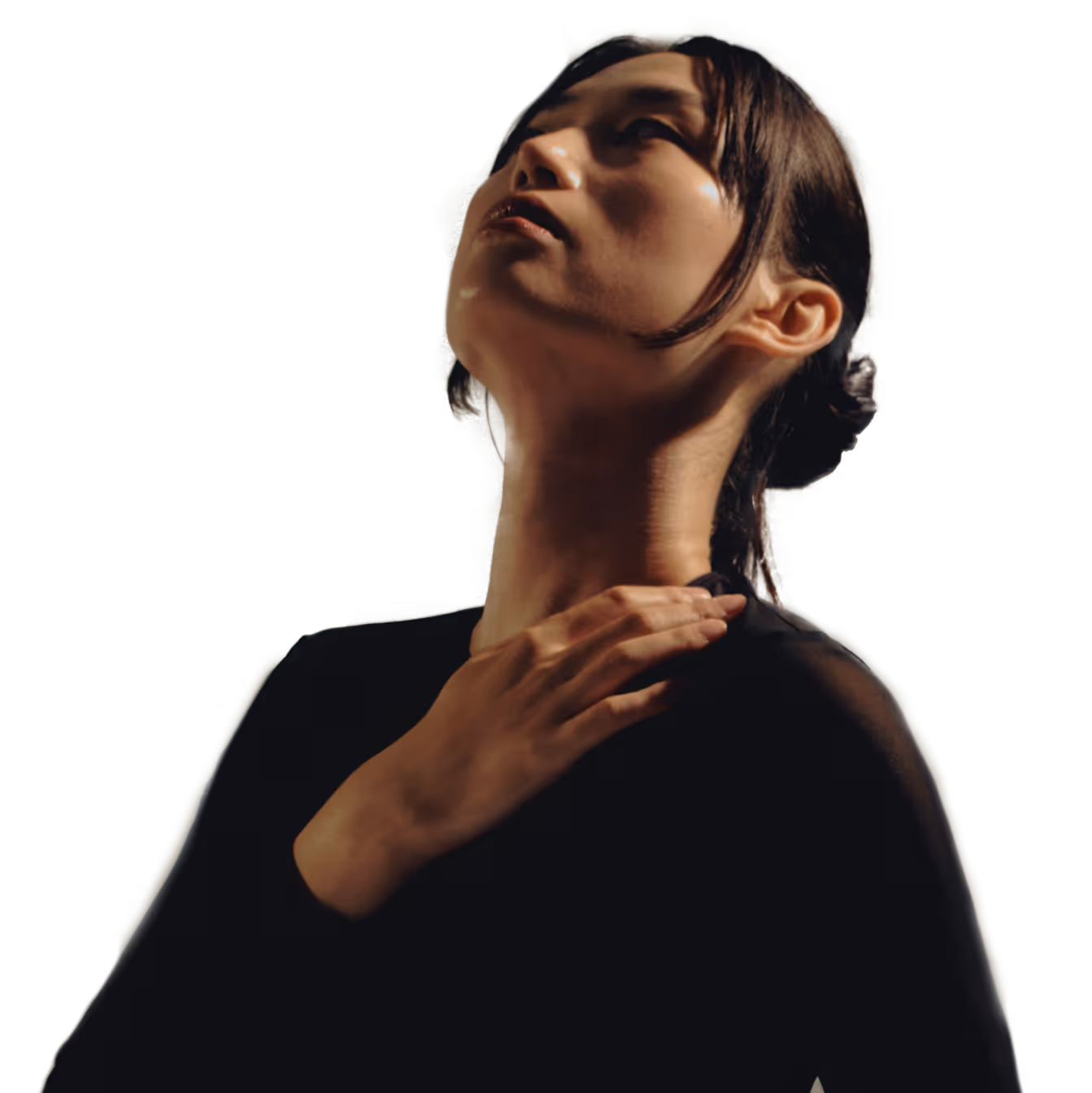A person in a black shirt looks upward, touching their chest with one hand.