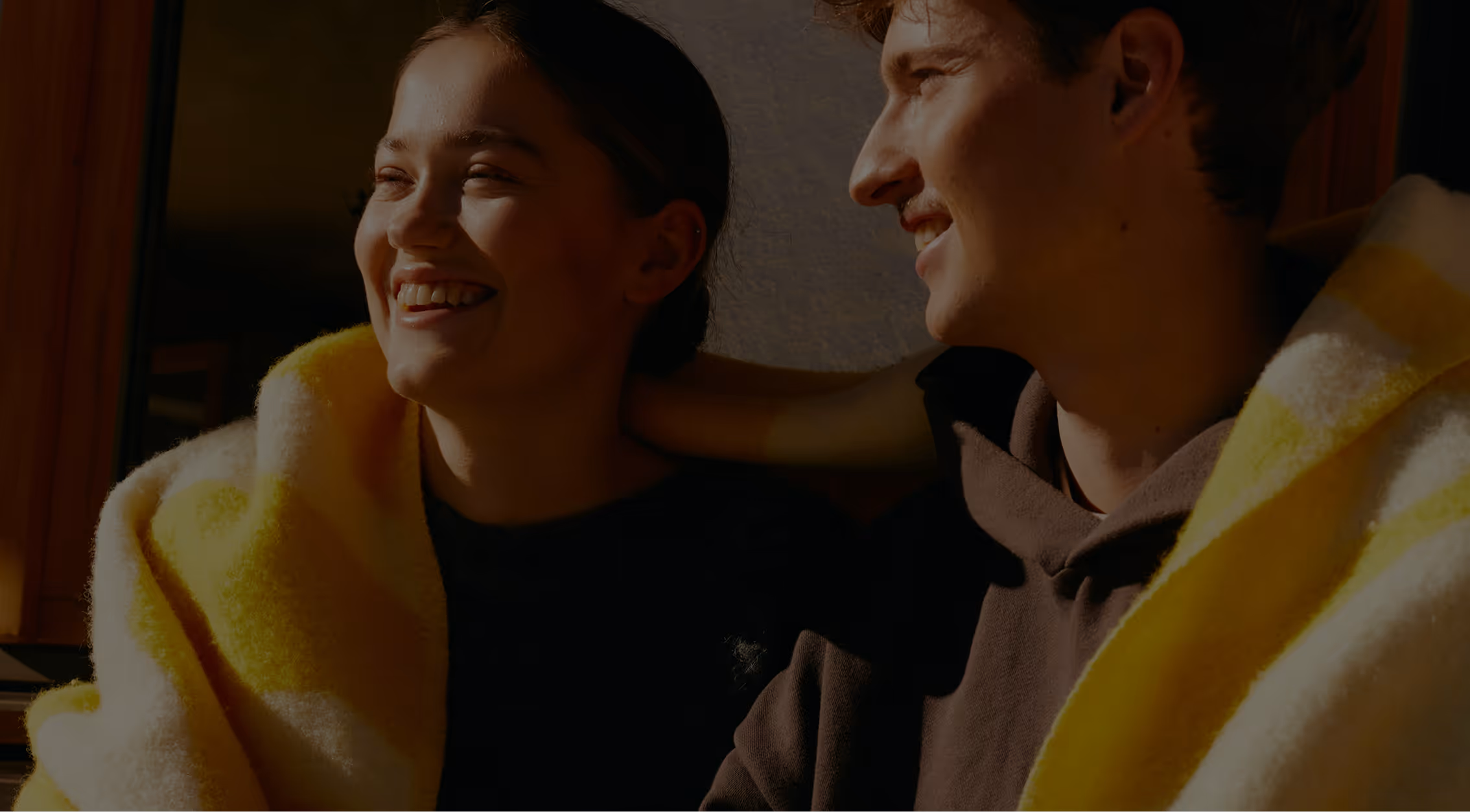 Couple wrapped in a blanket, smiling