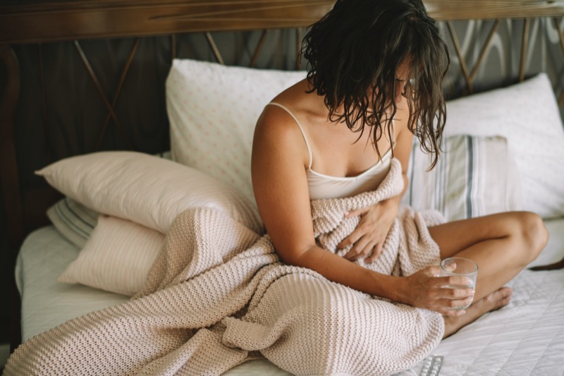Woman resting in bed holding her stomach