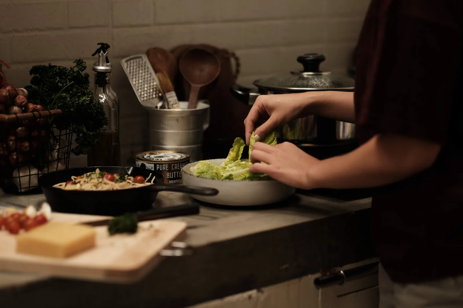 Hands tossing a lettuce salad in a home kitchen